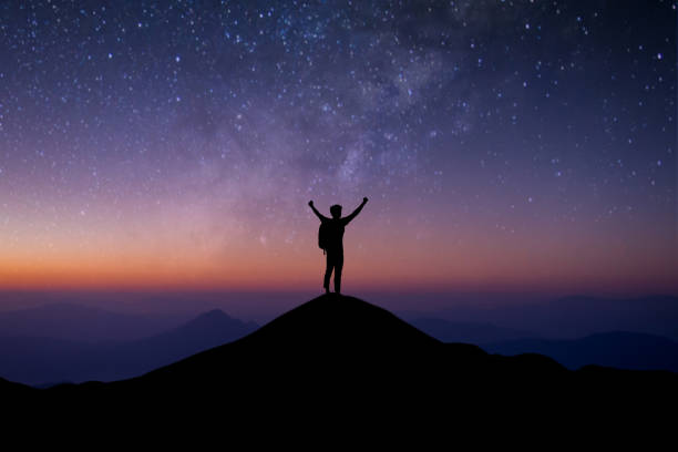istock Young traveler with backpack standing and open both arm watched night sky view, star and milky way alone on top of the mountain. He enjoyed traveling and was successful when he reached the summit. 1360012338