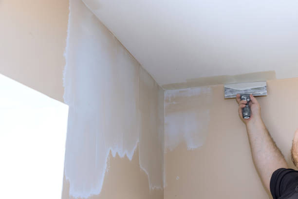 istock Plasterer smoothing wall surface with putty knife at home 1360013407