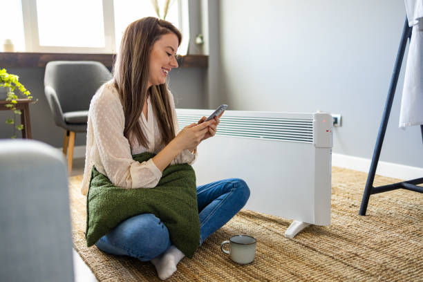 istock Woman and radiator using smartphone app for temperature control 1360014057