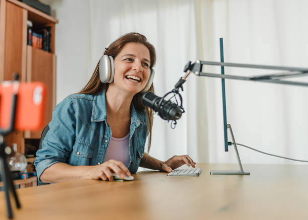 mulher feliz em fones de ouvido gravando podcast e usando computador - blog internet podcast computer keyboard - fotografias e filmes do acervo