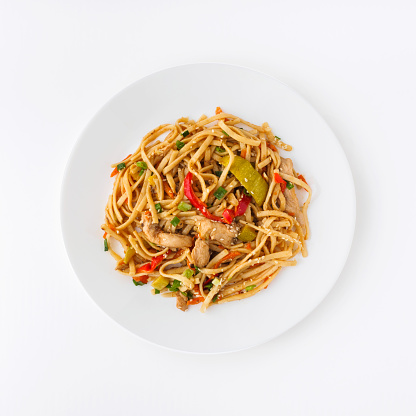 Asian food Udon noodles with fresh vegetables and chicken on white plate isolated on white background. Top view.