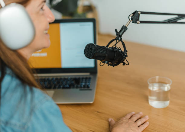 istock Woman recording podcast at table with mic 1360016935