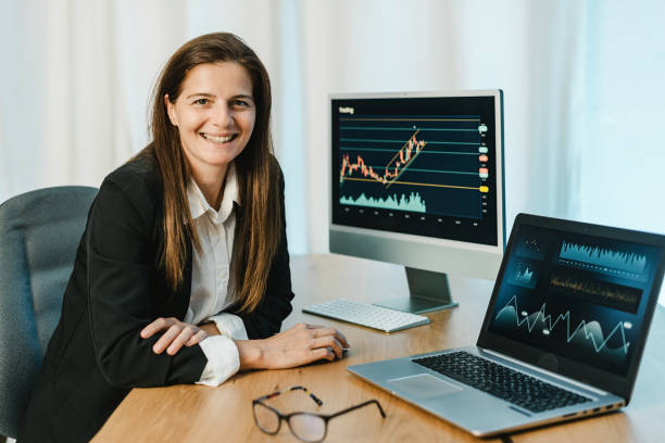 istock Cheerful woman trading on binary option in office 1360019759