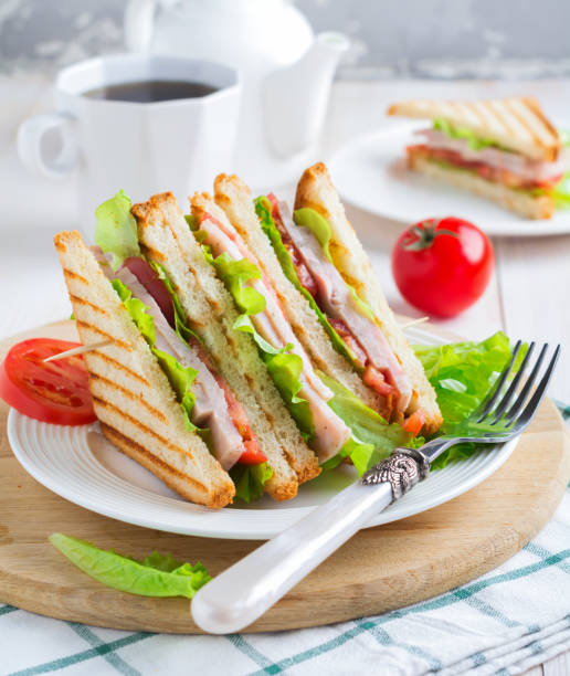 istock Sandwich for breakfast with stuffed tomatoes with ham and lettuce on a light wooden background. Selective focus. 1360019773