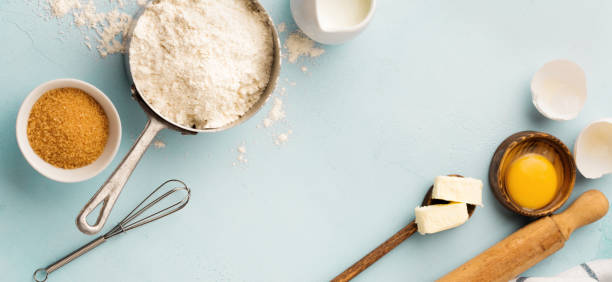 istock Baking background with ingredients flour, eggs, sugar, butter, cinnamon, anise star and kitchen tools on blue rustic table. Selective focus. Top view. 1360019972