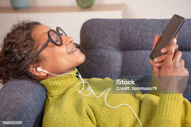 Black Woman Relaxing And Listening To Music Holding Phone Stock Photo - Download Image Now