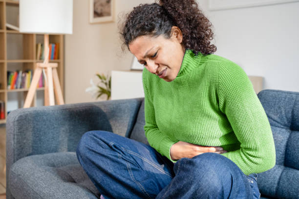 Black woman suffering heartburn and stomach pain Black woman suffering stomachache at home on the sofa gastroenteritis stock pictures, royalty-free photos & images
