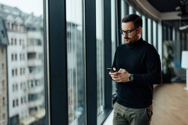 istock Pensive caucasian entrepreneur, typing on his phone in and thinking. 1360023896