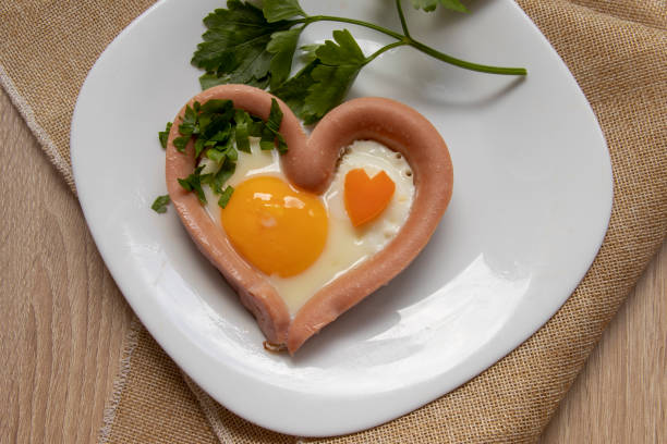 istock Romantic breakfast, heart-shaped scrambled eggs with sausage 1360024926