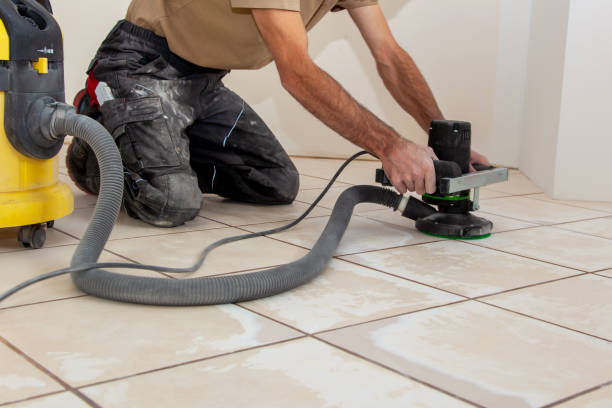 Preparation for an even floor to installing a new thin vinyl as a floor covering. el hombre está trabajando con una rectificadora de pisos eléctricos. rectificado de la superficie del piso de baldosas por máquina amoladora para una base lisa. preparación para un piso uniforme para instalar un nuevo vinilo delgado como revestimiento
