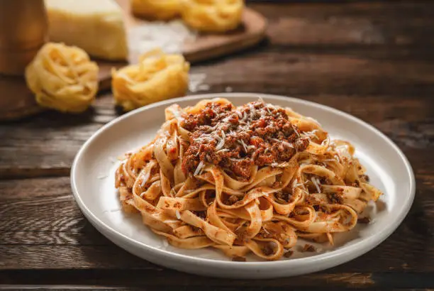 Close up plate of pasta tagliatelle with BOLOGNESE SAUCE on wooden table