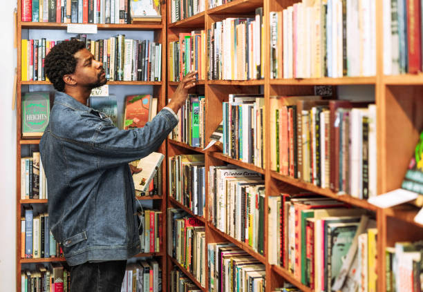Looking for a book A man browsing the shelves of an independent bookstore. bookstore stock pictures, royalty-free photos & images
