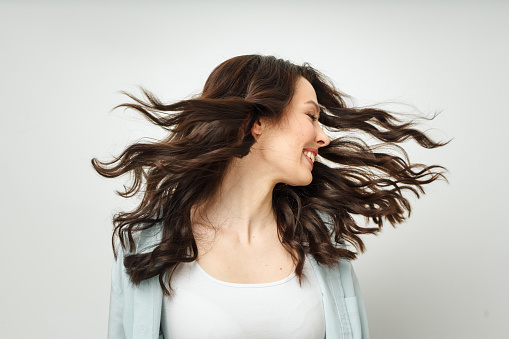 Portrait of a beautiful cheerful brunette with flowing curly hair, smiling, laughing, on a white background