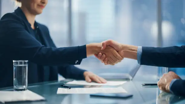 Photo of Female and Male Business Partners Sign Successful Deal Documents and Shake Hands in Meeting Room Office. Corporate CEO and Investment Manager Handshake on a Lucrative Financial Opportunity.