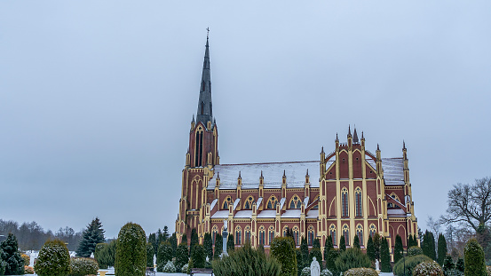 Panoramic view of neo-Gothic cathedral church in the town of Gervyaty in Belarus in the winter on dramatic sky background. Space for text. Religion and historical heritage concepts.
