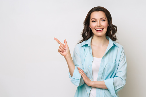 Young woman smiling and gesturing to copy space