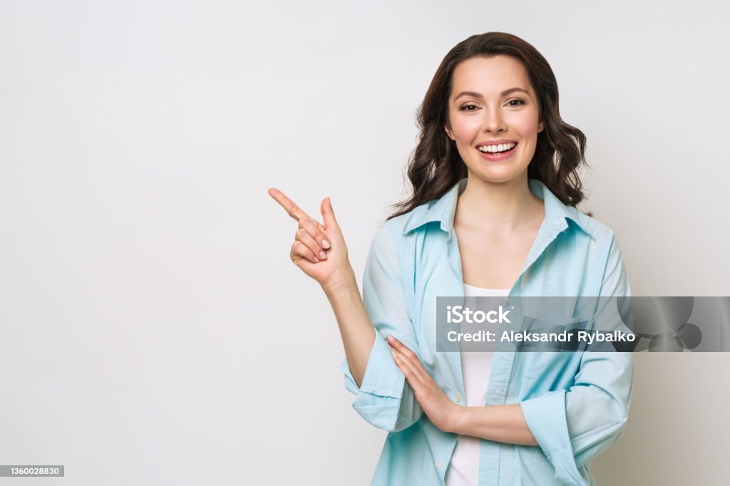 Young woman smiling and gesturing to copy space Women Stock Photo