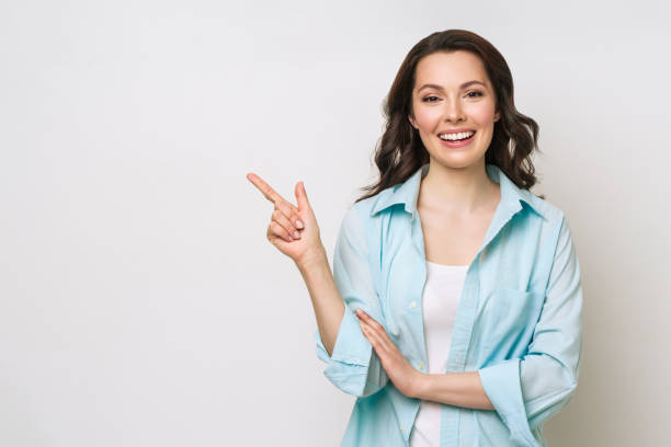 Young woman smiling and gesturing to copy space Young woman smiling and gesturing to copy space one woman only stock pictures, royalty-free photos & images