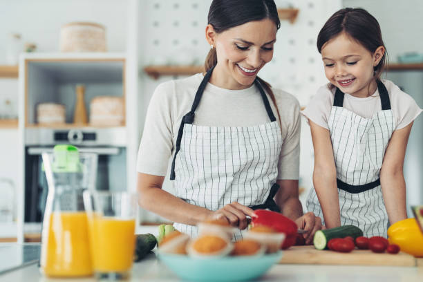 istock Little girl watching her mom preparing salad 1360028853