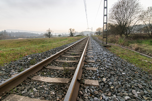 A narrow railroad track in a rural area at sunset