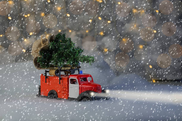 a fire department car is carrying a Christmas tree, it is snowing, a blizzard, headlights are on, bokeh