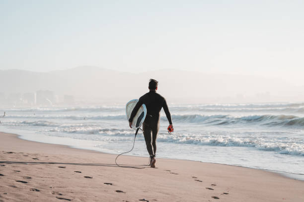 surfer, der mit einem surfbrett am strand spazieren geht, um in la serena, chile, ins meer zu gelangen - coquimbo region stock-fotos und bilder