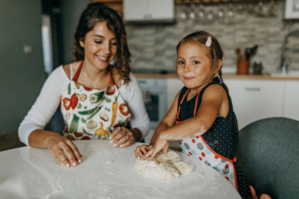 istock Mother and daughter knead dough 1360031512