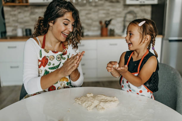 istock Mother and daughter knead dough 1360031514