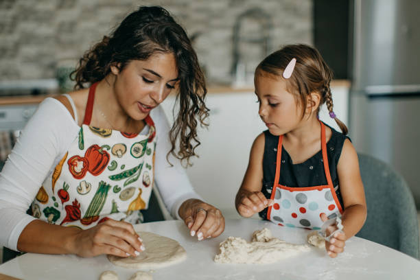 istock Mother and daughter knead dough 1360031519