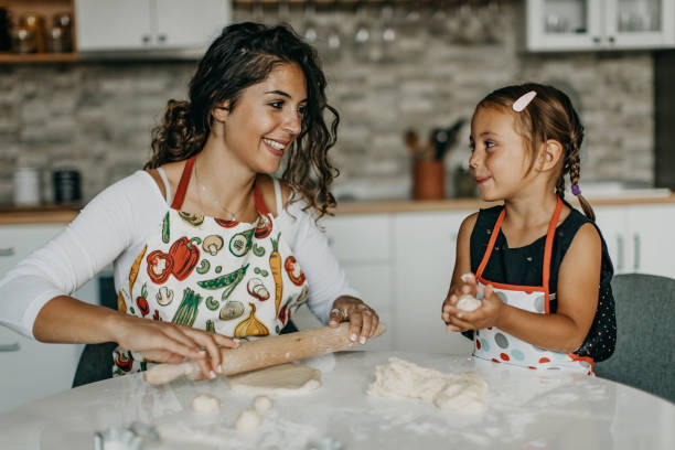 istock Mother and daughter knead dough 1360031520