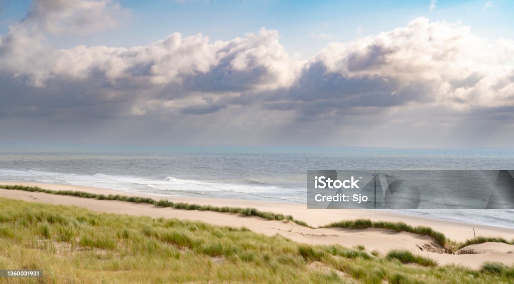 Summer in the dunes with clouds drifting over the sea Summer in the dunes at the North Sea beach with clouds drifting over the sea in the blue sky in the background. Beach Stock Photo
