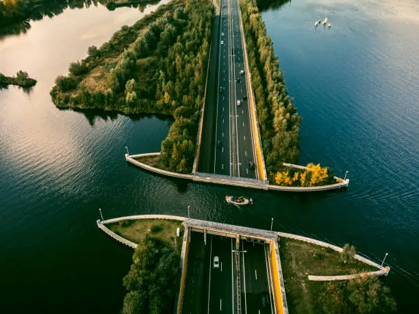 Aquaduct Veluwemeer in the Veluwe lake near Harderwijk where boats pass over the road. A pleasure yacht is sailing over the road where cars cross the water through a tunnel.