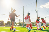 istock Members of female kids' soccer and football team training and dribbling to improve their skills 1360033206
