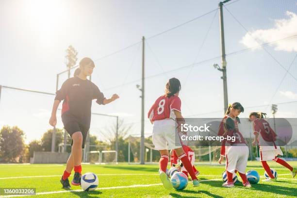 Members Of Female Kids Soccer And Football Team Training And Dribbling To Improve Their Skills Stock Photo - Download Image Now