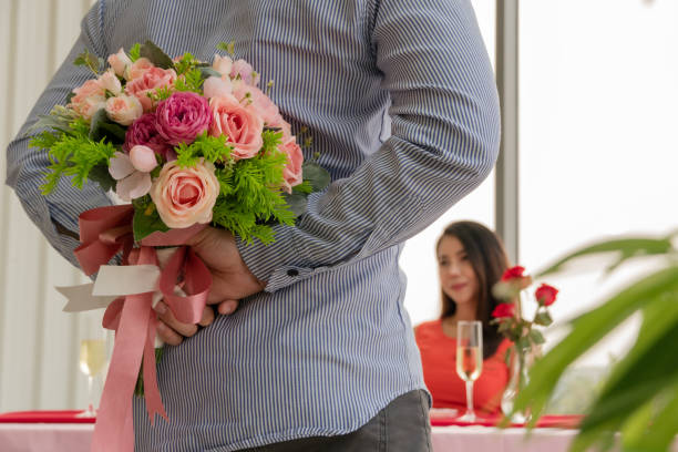 Asian man hiding flower to surprise his girlfriend on dating in Valentine's, Anniversary or birthday, focus on happy woman smile on face, attractive couple having dinner together Asian man hiding flower to surprise his girlfriend on dating in Valentine's, Anniversary or birthday, focus on happy woman smile on face, attractive couple having dinner together beautiful women giving head stock pictures, royalty-free photos & images