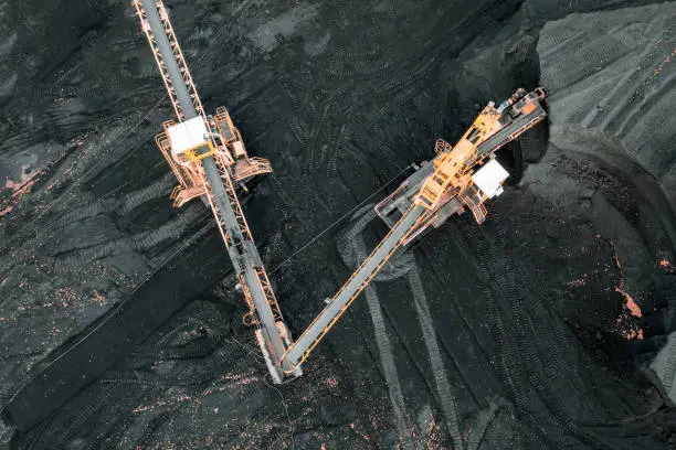 Photo of Large piles of coal, top view. Coal storage at the TPP, unloading and loading of coal by excavators and transport belts at the TPP warehouse. Aerial photography