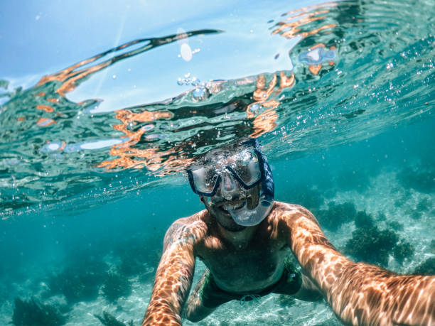 hombre snorkeling en vacaciones - snorkel fotografías e imágenes de stock