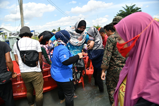 The members of Malaysian Armed Forces and the crowd helped a woman get off the boat at RTB Bukit Changgang, Dengkil, Sepang on December 20th, 2021.