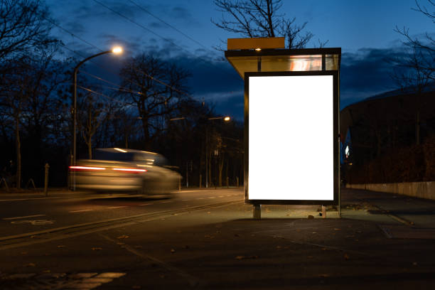 Blank Advertisement Board Template Blank advertisement board as a mock-up template in the city. Empty screen at a bus stop during the night. A car driver is passing by very fast. lightbox stock pictures, royalty-free photos & images