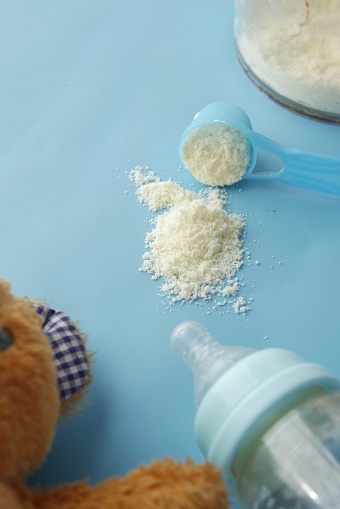 Close up of baby milk powder and spoon on tile background