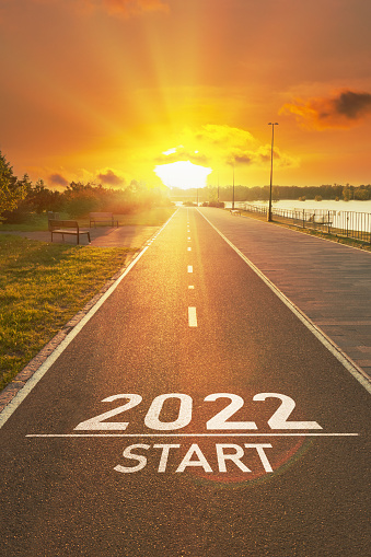New year 2022 start concept. The number of the 2022 year is written on the asphalt on the empty sports path in the bright rays of the sun. Motivational inscription for planning your life, business