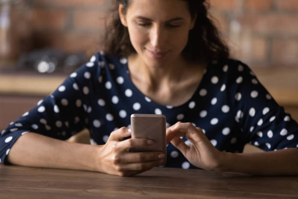 istock Smiling latin woman using smartphone, sitting at table. 1360045105