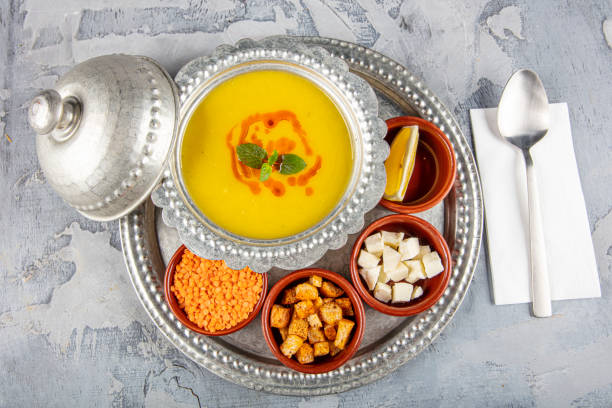 Lentil soup in a copper tray and copper bowl grey background.