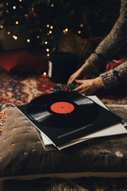 Christmas music LP record with multicolored sound equalizer wave line and flying musical notes against black background.