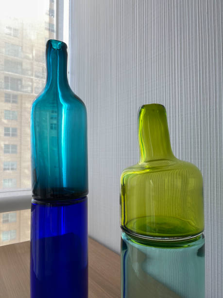 istock Blue and green decorative  glass bottles on reflective surface 1360054835