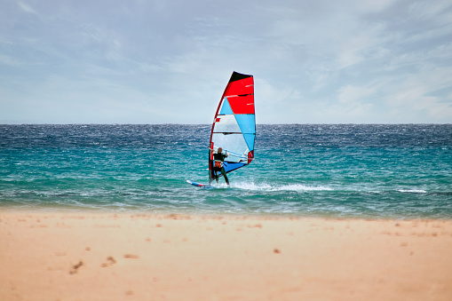 Aerial view photo of a young man windsurfing on the open sea. High angle view. Drone point of view.