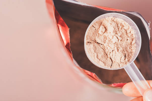 istock Whey protein measuring spoon chocolate flavor over open package 1360059106