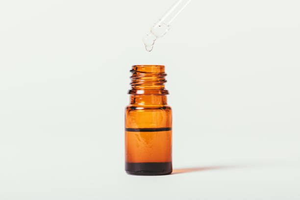 istock Essential oil dripping into bottle with dropper on white background 1360059133