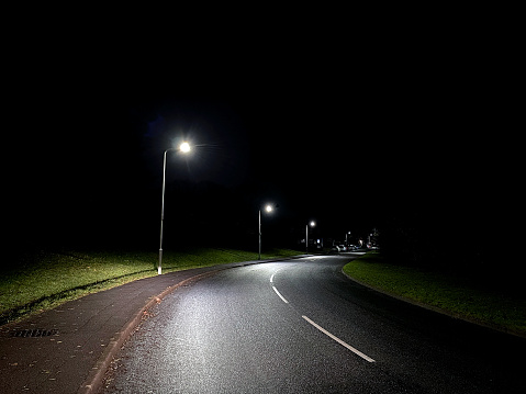 Deserted road at night lit by LED street lights. No people.