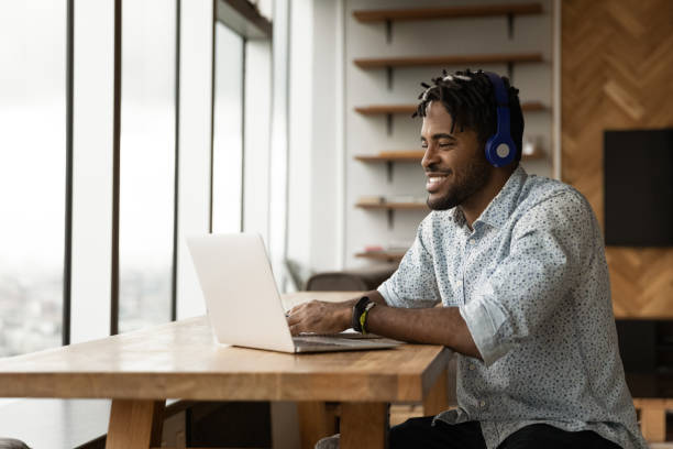 istock African guy using laptop listens audio course through headphones 1360060886